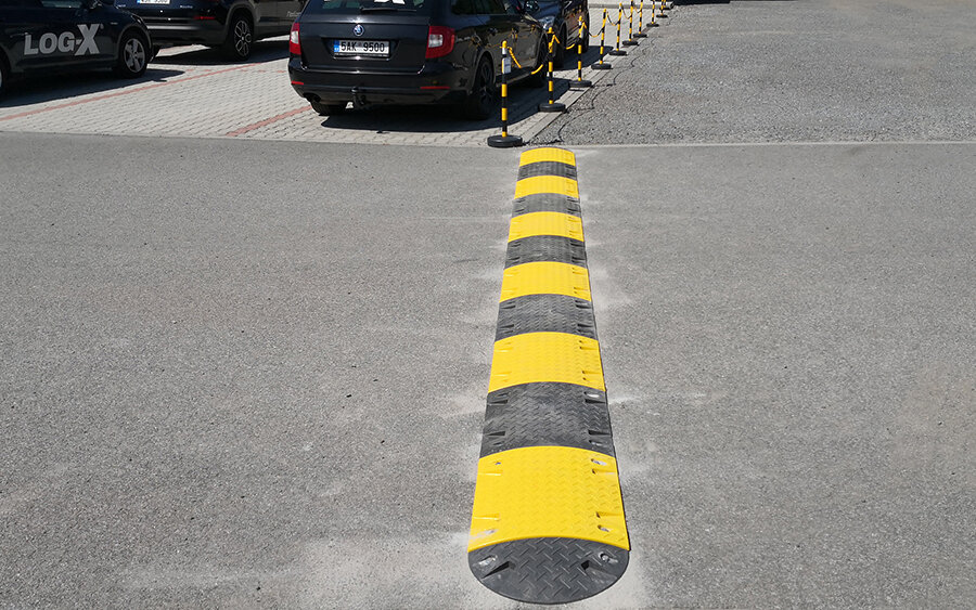 Zpomalovací práh a vymezovací sloupky s řetězem na velkém parkovišti